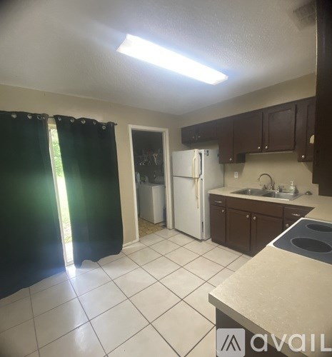 A kitchen with white tiles and a white fridge.