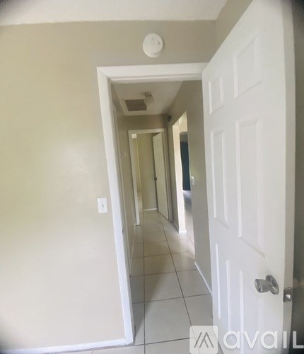 A hallway with a white door and tiled floor.