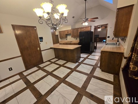 A kitchen with a black refrigerator and wooden floors.
