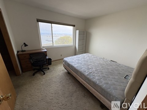 A bedroom with a large bed, desk, and chair.