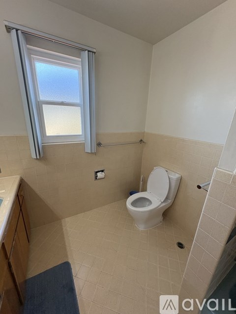 A bathroom with a toilet, sink, and window.