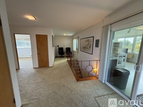 A living room with a staircase and a glass door leading to a balcony.