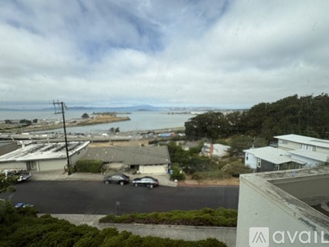 A view from a high vantage point looking down at a parking lot and buildings with a body of water in the distance.