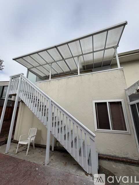 A patio with a white railing and a white chair under a white awning.