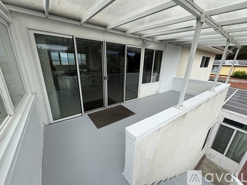 A balcony with a white railing and glass doors.