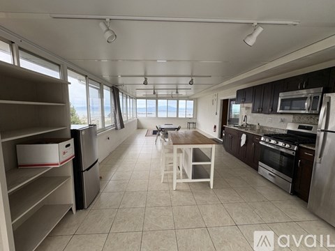 A kitchen with a refrigerator, oven, and a table with a chair.