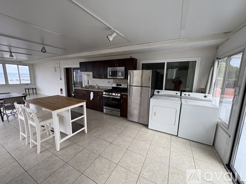 A kitchen with white appliances and a table with chairs.