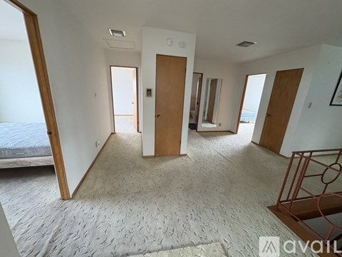 A room with a carpeted floor and a bed in the corner.