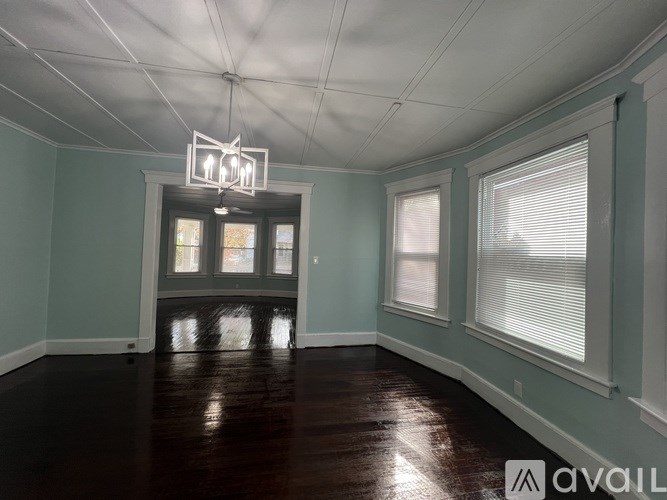 A room with a wooden floor and a window with blinds.