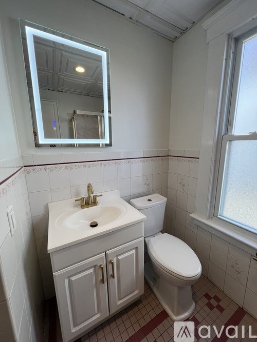 A bathroom with a toilet, sink, and mirror.