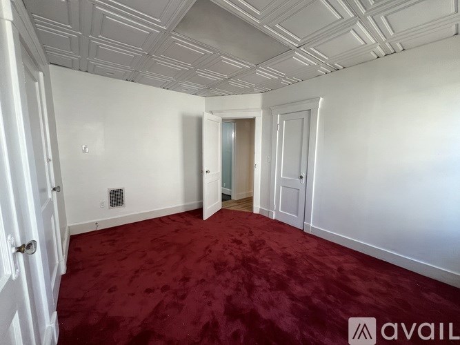 A room with a red carpet and white walls.