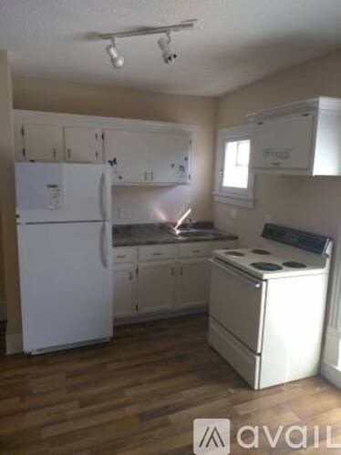 A kitchen with white appliances and wooden floors.