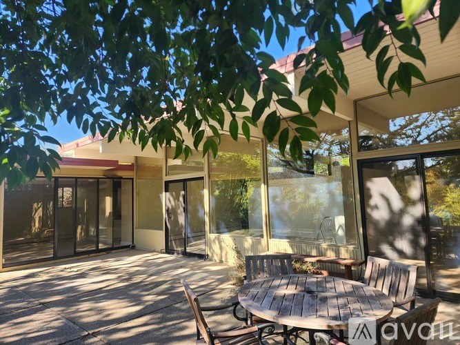 A patio with a table and chairs is surrounded by trees.