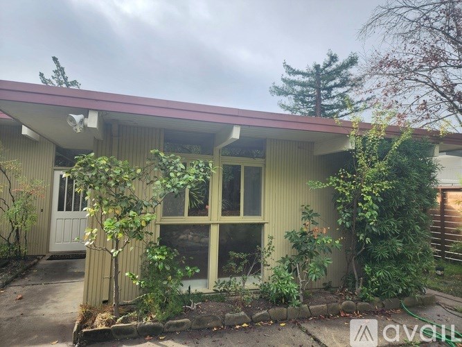A house with a red roof and a white door surrounded by greenery.
