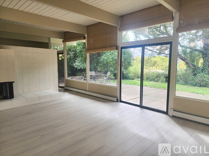 A spacious room with a fireplace and large windows overlooking a garden.