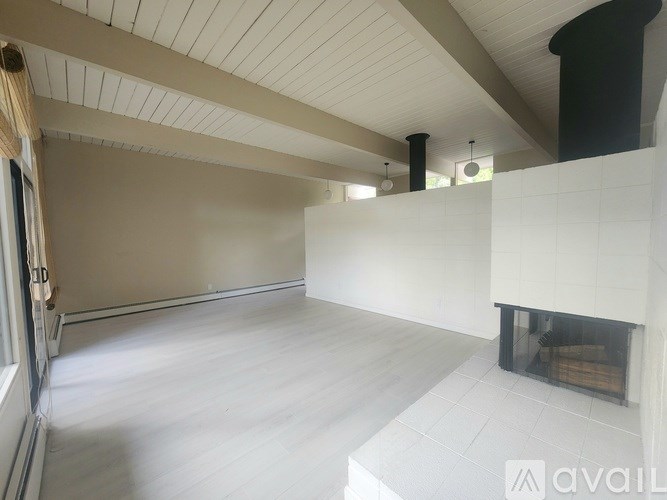 A spacious room with a fireplace and a large window.