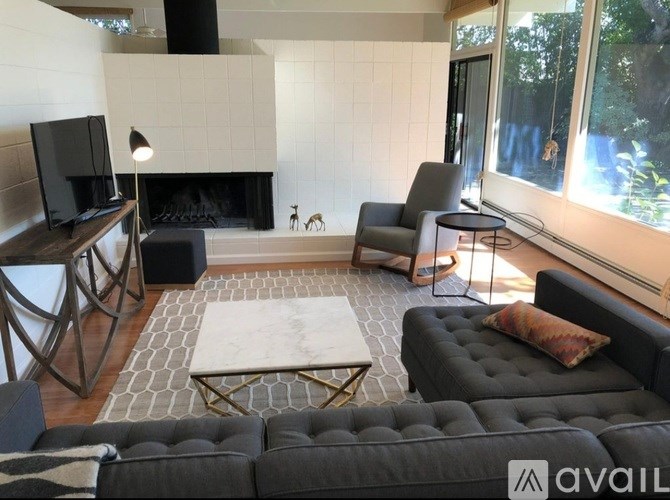 A living room with a black couch, a fireplace, and a television.
