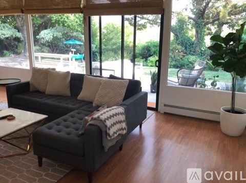 A black couch with a white pillow and a grey throw blanket sits in a living room.