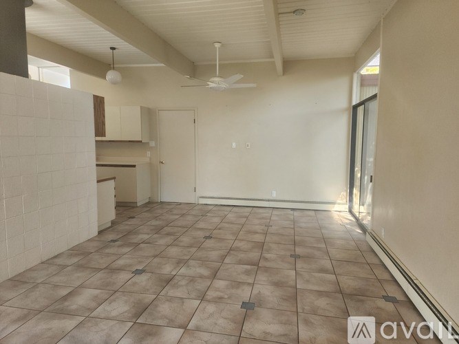 A spacious room with tiled flooring and a ceiling fan.