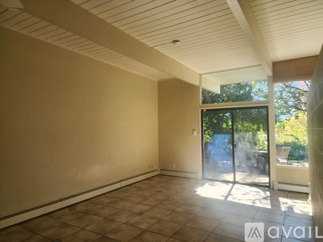 Empty room with tiled floor and sliding glass door leading to a backyard.