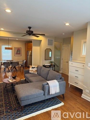 A living room with a grey couch and a rug.