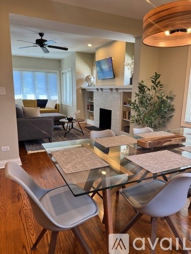 A living room with a glass table and grey chairs.