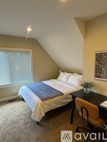 A bedroom with a bed, desk, and window.