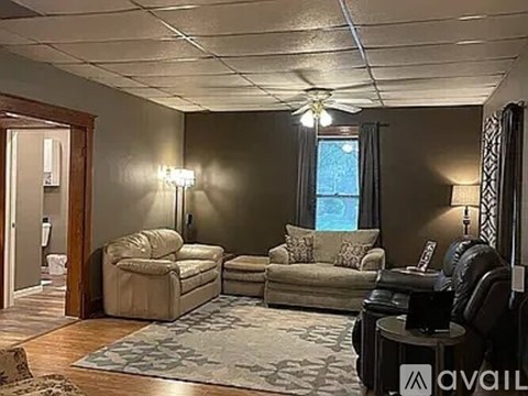 A living room with a beige couch, a chair, and a table with a lamp on it.