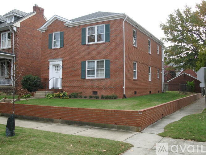 A red brick house with green shutters and a white door.