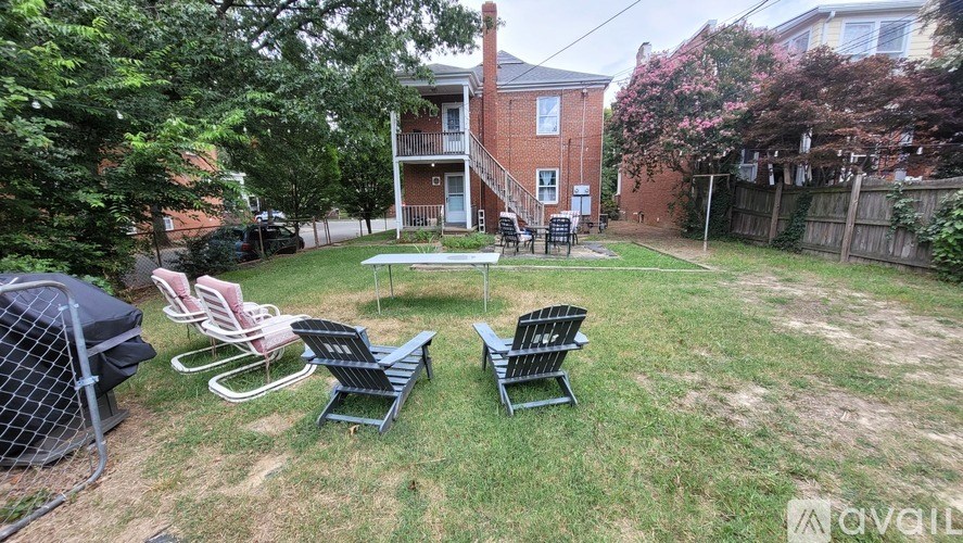 A backyard with a lawn, chairs, and a fence.