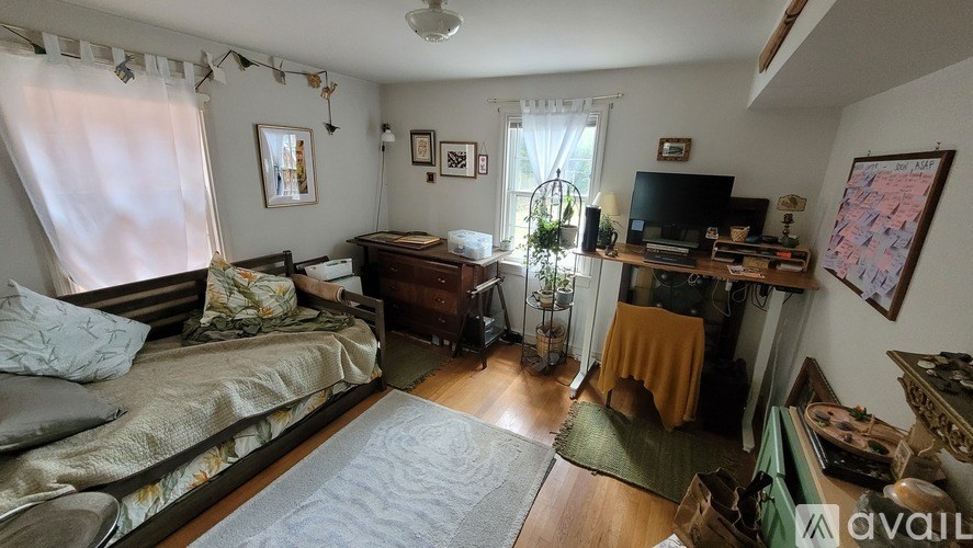 A bedroom with a bed, a desk, and a window with curtains.