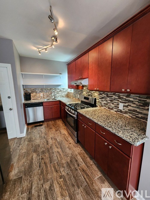 A kitchen with red cabinets and a granite countertop.