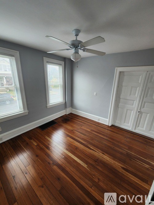 A room with a ceiling fan and wooden flooring.
