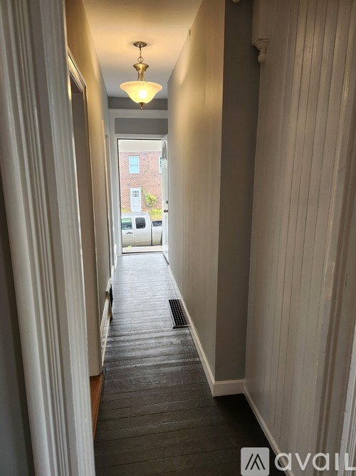 A long hallway with a light on the ceiling and a window in the distance.
