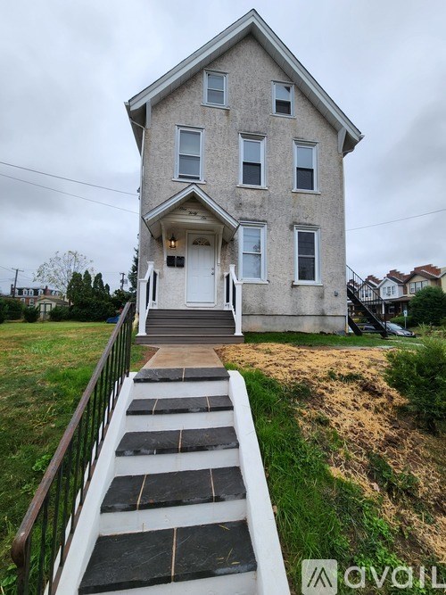 A two-story house with a front porch and a staircase leading to the front door.