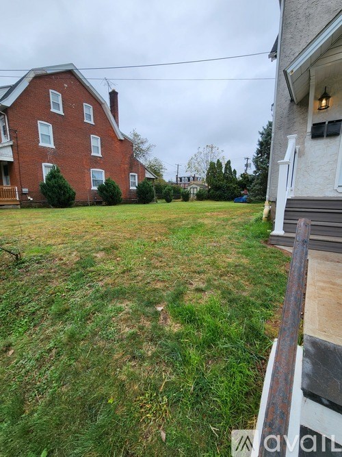 A grassy backyard with a red brick house in the background.