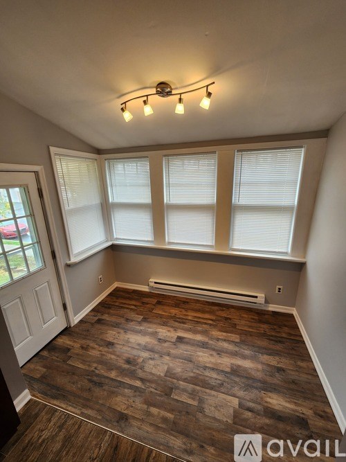 A room with wooden flooring and a window with blinds.