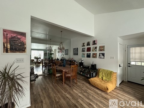 A living room with a yellow bean bag chair and a dining table with chairs.
