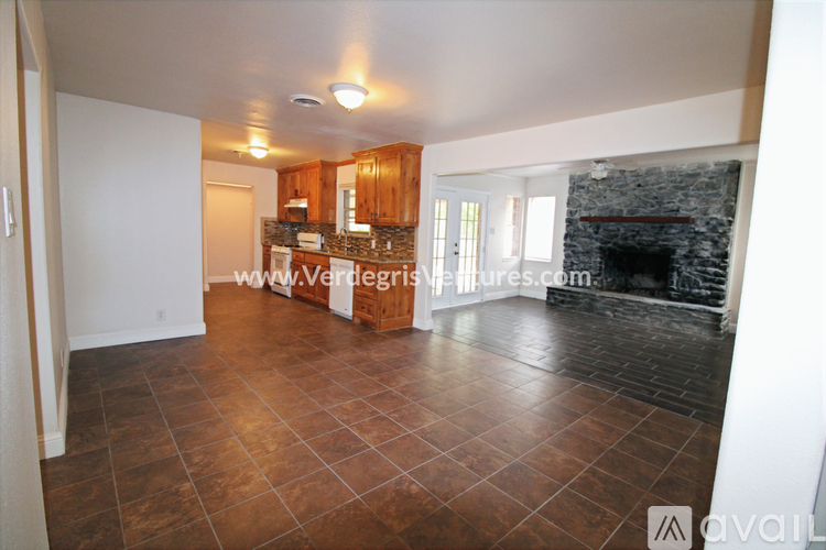 A living room with a stone fireplace and wood flooring.