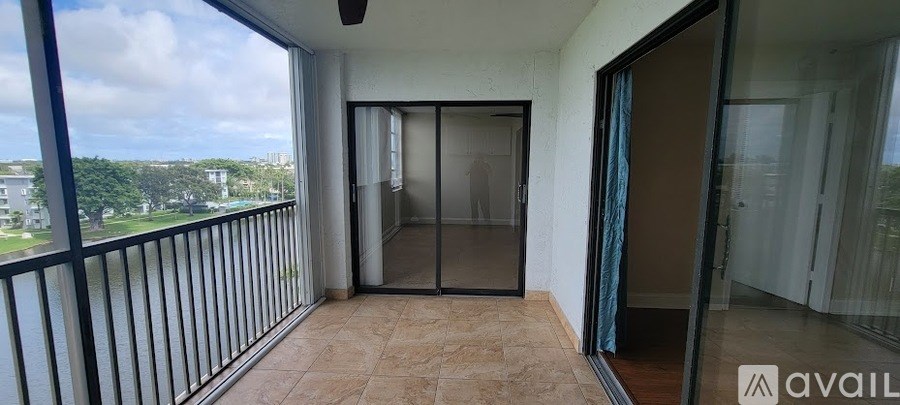 A balcony with a glass door leading to a room.