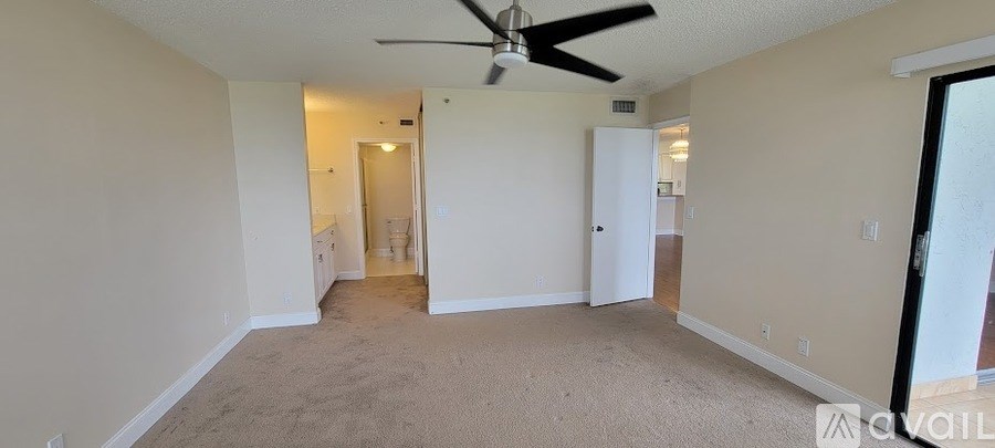 A room with a ceiling fan and carpeted floor.