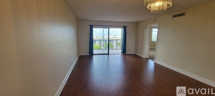 A spacious room with wooden floors and a large window with sliding glass doors.