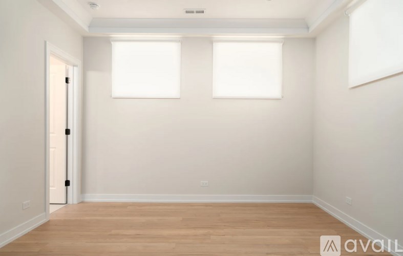 A room with wooden flooring and two windows.