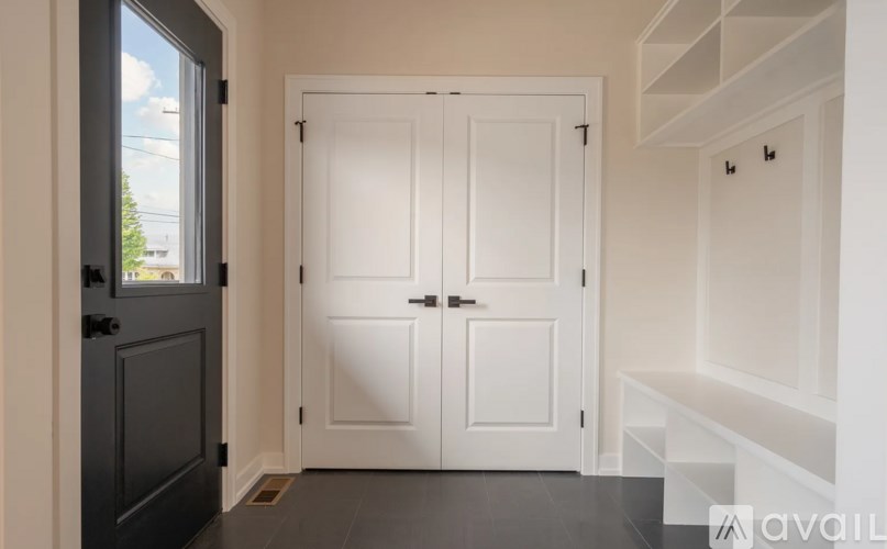 A white door is in a room with a window and a shelf.