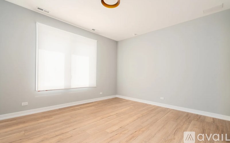 A room with wooden flooring and a window with blinds.