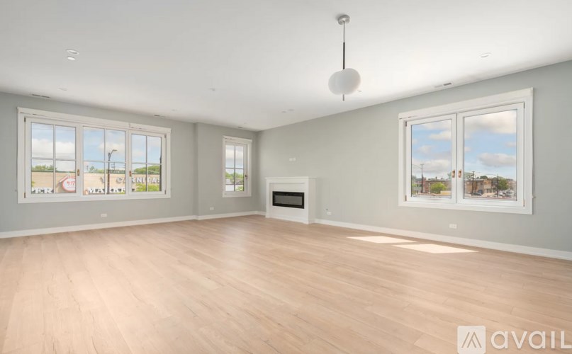 A spacious room with wooden floors and large windows.