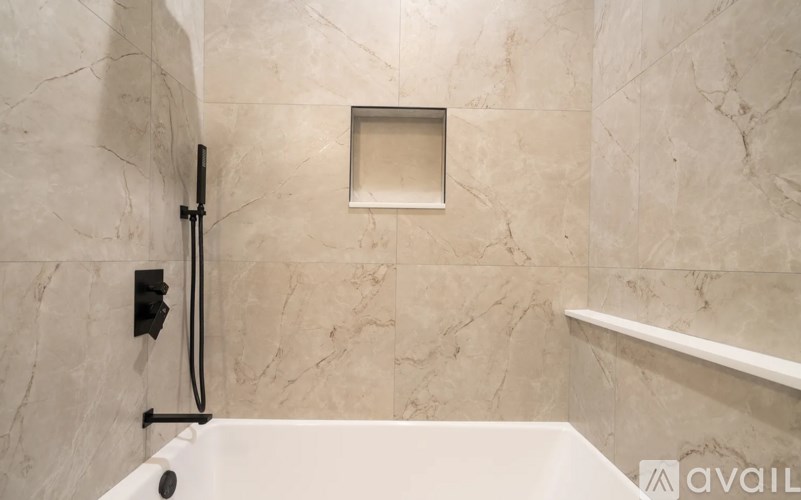 A bathroom with a marble wall and a white bathtub.