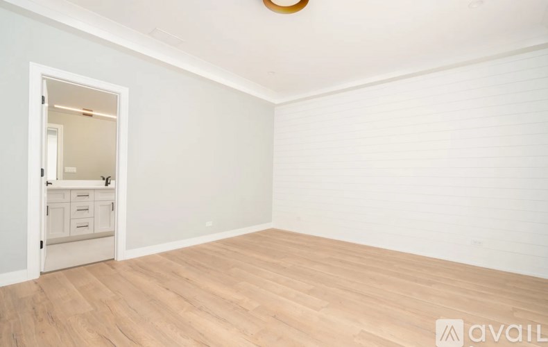A room with wooden flooring and a white door leading to another room.