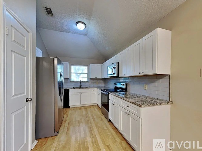 A kitchen with white cabinets and a wooden floor.
