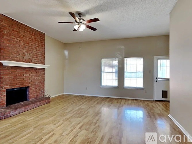 A room with a brick fireplace and wooden floors.